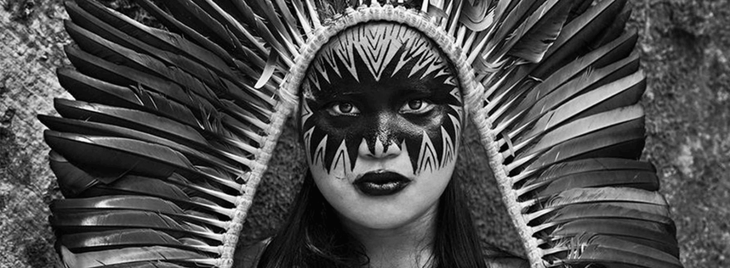 Primer plano de una mujer indígena con tocado ceremonial y pintura facial, fotografiada por Sebastião Salgado en la Amazonia.