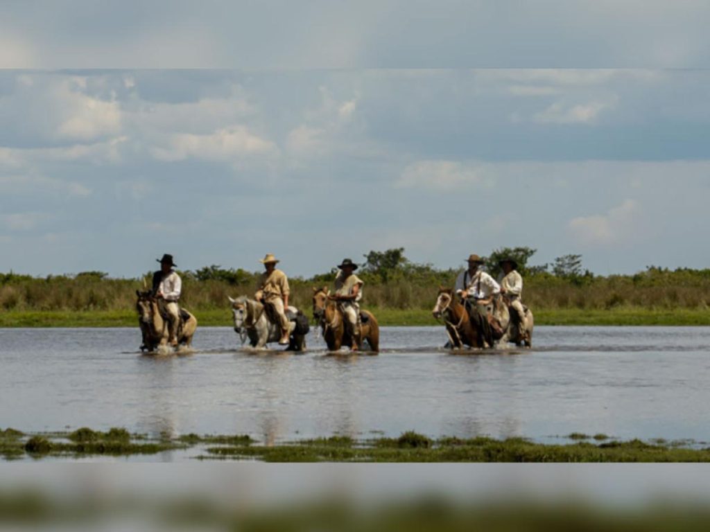 Jinetes cruzando un río en una escena de la serie La vorágine, inspirada en la novela de José Eustasio Rivera.