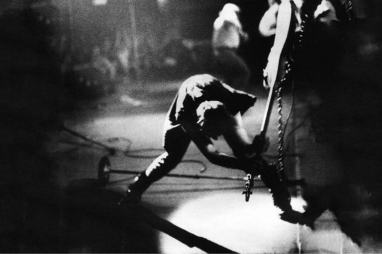 Paul Simonon de The Clash rompiendo su bajo en el escenario, 1979.