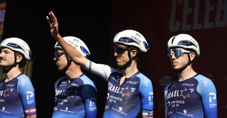 Ciclistas del Israel Premier Tech alineados antes de la salida; uno saluda al público durante la Vuelta a España 2025.