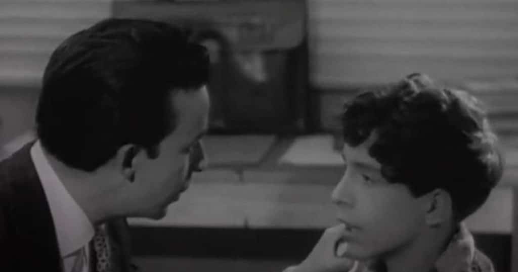 Hombre y niño conversan en una escena en blanco y negro de La frontera del sueño.