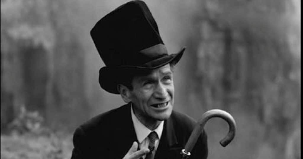 Hombre con sombrero de copa y bastón curvo, en una escena en blanco y negro de La frontera del sueño.