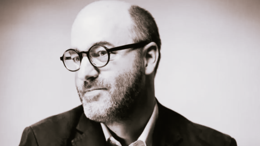 Alain Deneault, filósofo canadiense, autor de Mediocracia, en retrato con gafas redondas y traje oscuro