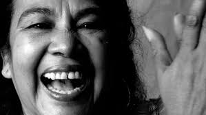 Primer plano en blanco y negro de Totó la Momposina cantando y sonriendo durante una presentación.