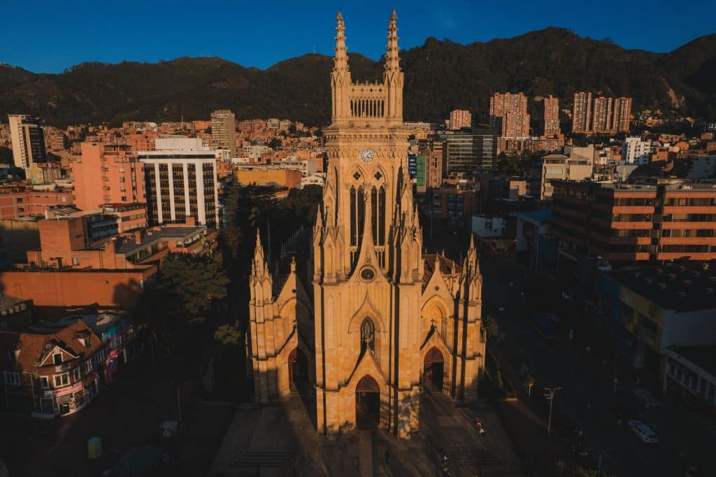 Vista aérea de la Iglesia de Lourdes en Chapinero, Bogotá, al atardecer, con los cerros orientales de fondo